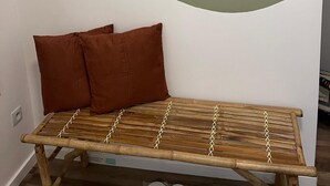 Ein Zimmer mit einer hölzernen Sitzbank, einem Spiegel und einem Regal mit Vase und Zahnbürste.