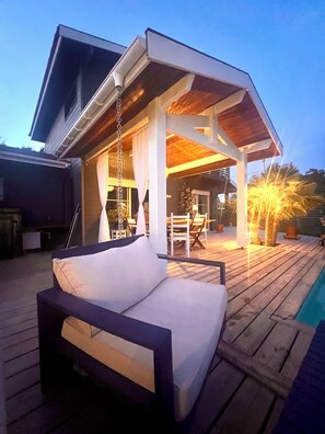 A modern outdoor patio with a wooden deck, a hanging chair, and a pool. - House between pond and ocean - ideal for a family (Lège-Cap-Ferret)