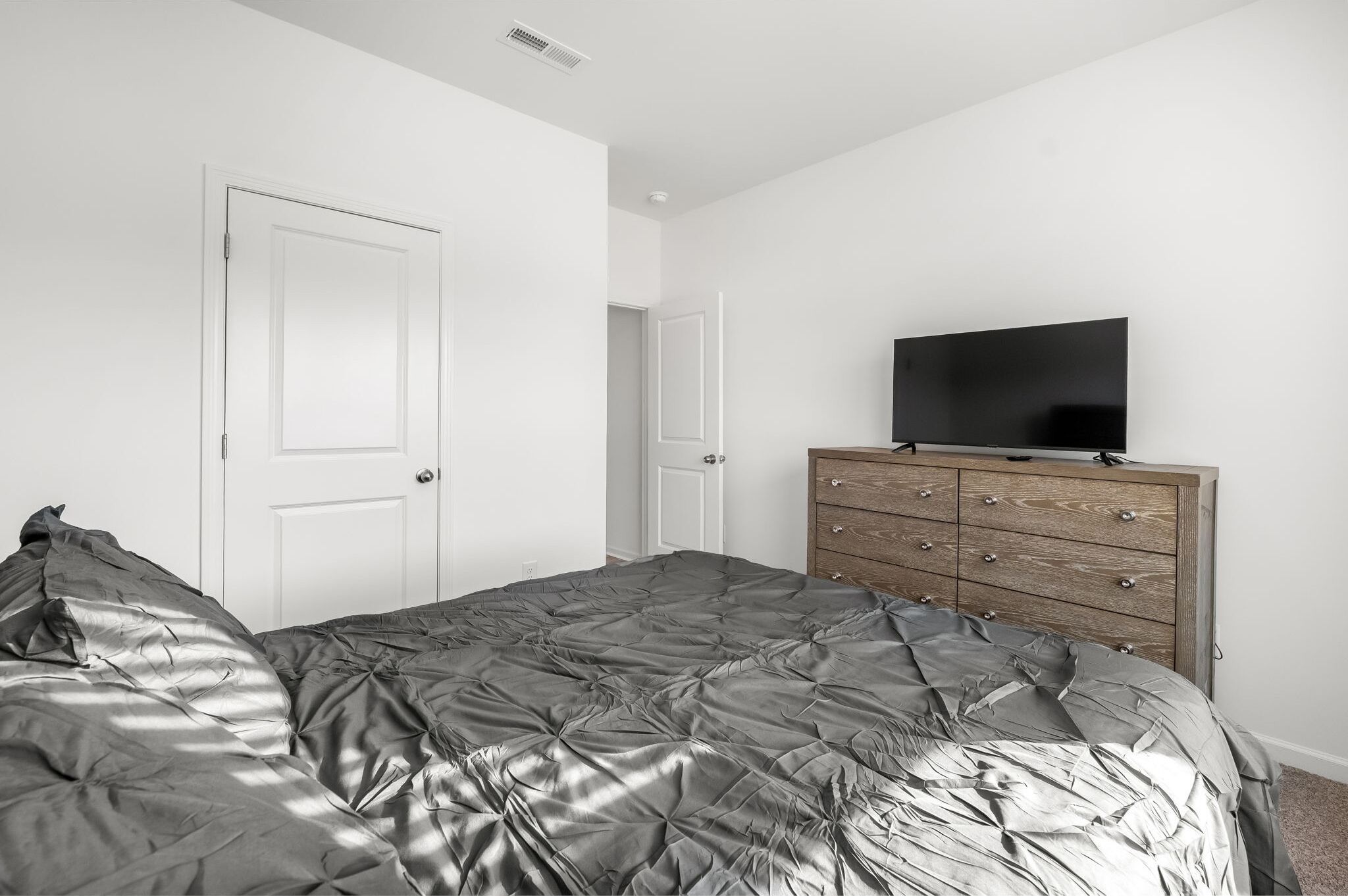 A bedroom with a bed, a dresser, and a television.