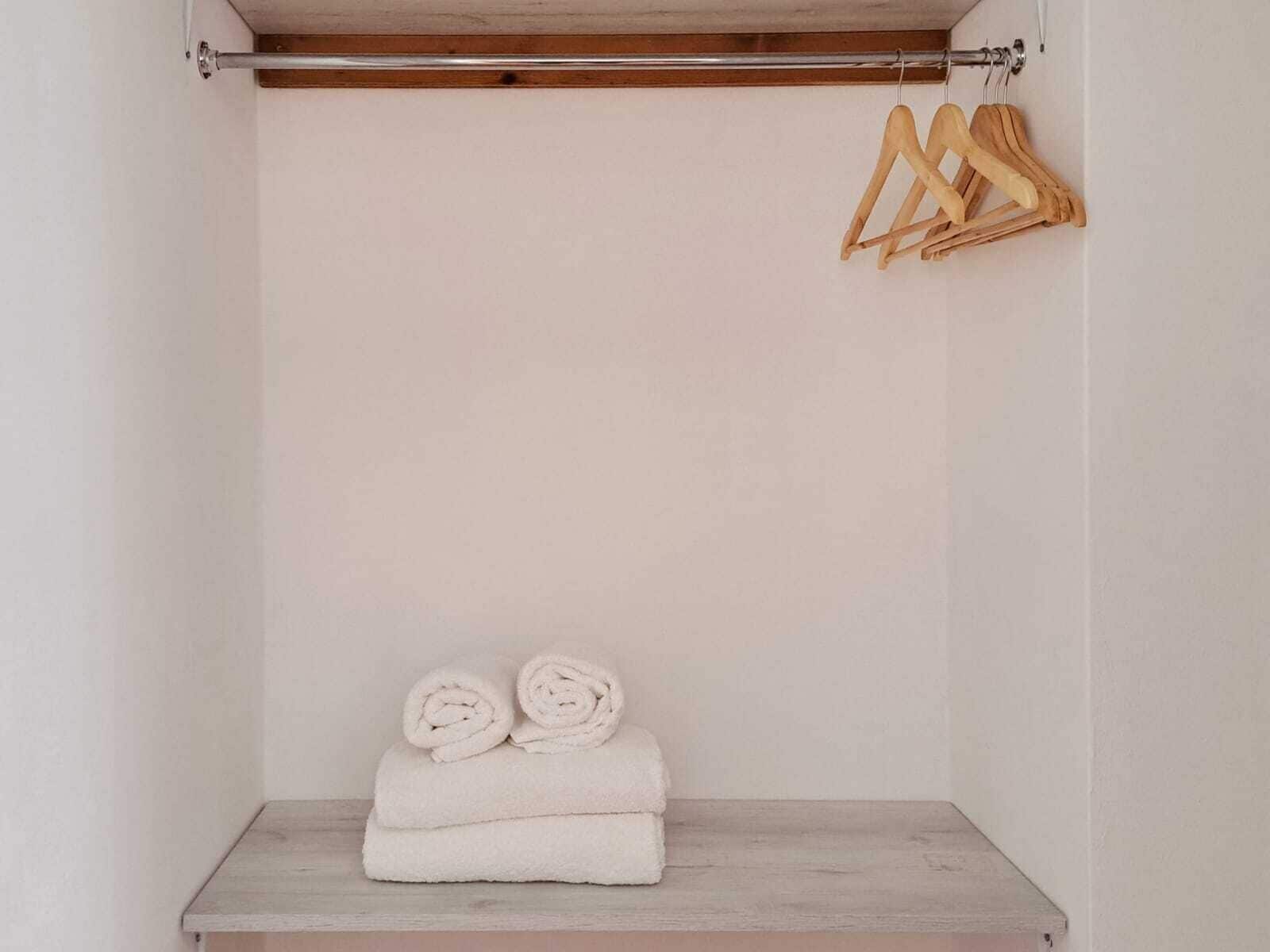 Une pièce avec une étagère en bois où sont rangées des serviettes pliées et des cintres en bois accrochés au mur.