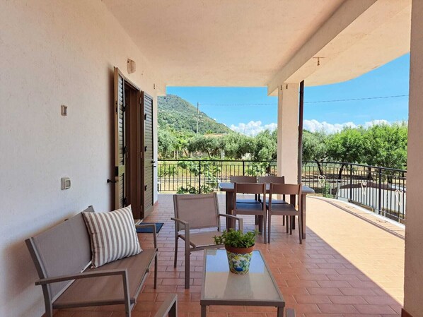 A balcony with a table, chairs, a sofa, and a potted plant.
