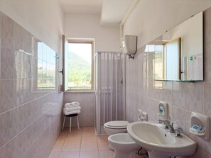 A bathroom with two toilets, a sink, a mirror, and a towel rack.