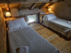 Une pièce chaleureuse et rustique, dotée de deux lits simples, de planchers en bois et de poutres apparentes.