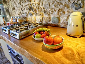 Une cuisine équipée d’une cuisinière à gaz, d’un grille-pain et de plusieurs bols remplis de fruits posés sur le comptoir.