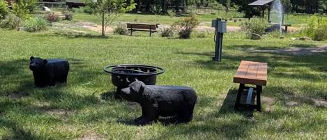 Een park met een picknicktafel, een bankje en twee beerbeelden.