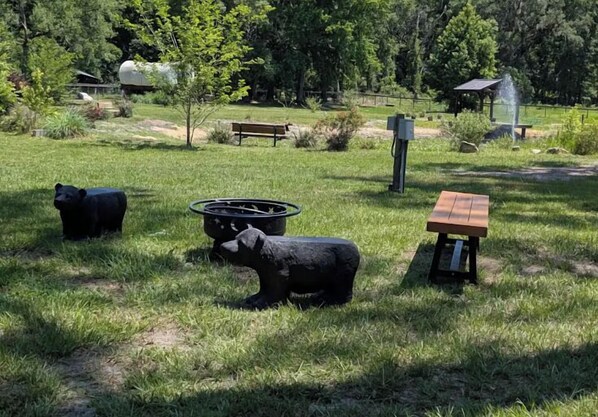 Un parque con una mesa de picnic, un banco y dos estatuas de osos.