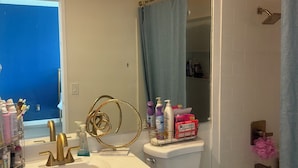 Ein Badezimmer mit Waschbecken in Weiß, goldenen Armaturen, Toilette und Badewanne.