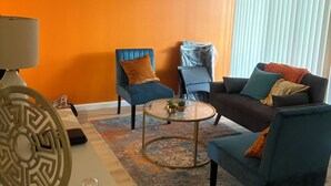 Ein Wohnzimmer mit einem blauen Sofa, zwei Sesseln, einem Couchtisch und einer Lampe.