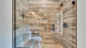 Una ducha moderna con paredes de vidrio y suelo de mosaico.