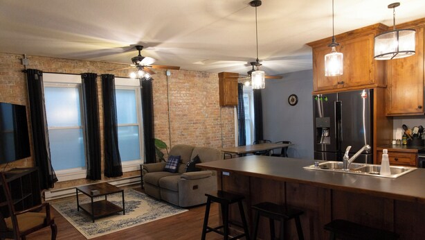 Una cocina moderna con una isla central, taburetes de bar y un refrigerador empotrado.