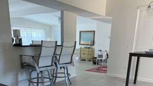 A spacious kitchen with a black countertop, a dining area with chairs and a table, and a view into another room with a ceiling fan. - Port Charlotte 3-2 waterfront home with dock and river view (Port Charlotte)
