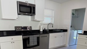 A modern kitchen with white cabinets, stainless steel appliances, and a grey tiled floor. - Port Charlotte 3-2 waterfront home with dock and river view (Port Charlotte)