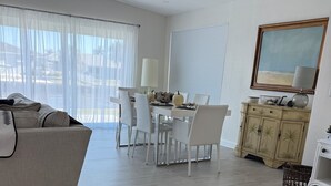 A spacious living area with a dining table, white chairs, a beige sofa, and a decorative cabinet. - Port Charlotte 3-2 waterfront home with dock and river view (Port Charlotte)
