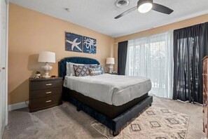 Ein Schlafzimmer mit Bett, Nachttischen, Deckenventilator und Kunstwerken an der Wand.