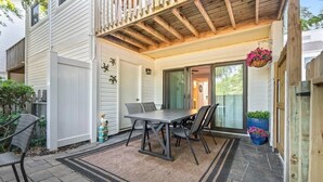 A patio with a table and chairs, a wooden ceiling, and a sliding glass door leading to a covered area. - One Block from the Beach. Beautiful 2 Bedroom 2.5 Bathroom Condo. (Myrtle Beach)