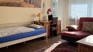 A bedroom with a bed, desk, chair, and a red sofa.
