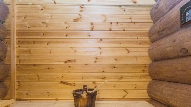 L’intérieur d’une cabane en bois, avec un petit seau en bois posé sur une étagère.