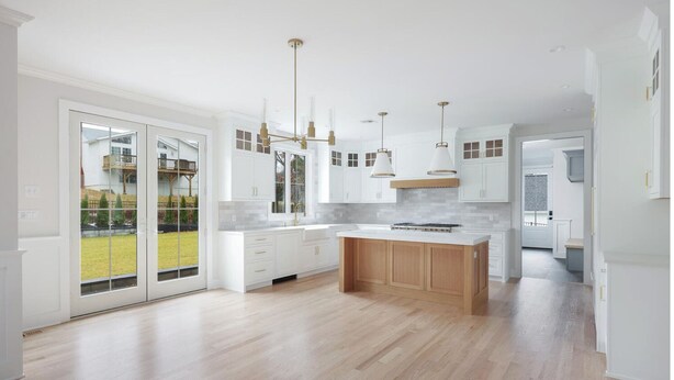 Une cuisine moderne avec des meubles blancs, un îlot central en bois et des luminaires suspendus.