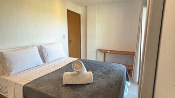 Hotellihuone, jossa on sänky, pieni pöytä ja ovi.