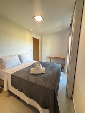 A hotel room with a bed, a small table, and a door. - Villa Visgo Itacaré (Itacaré)