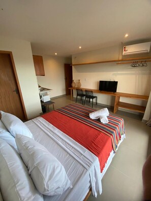 A hotel room with a bed, a desk, a chair, a television, and a wardrobe. - Villa Visgo Itacaré (Itacaré)