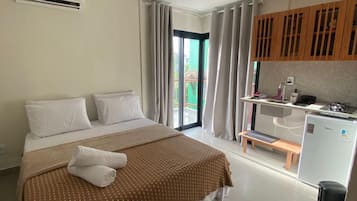 Ein Hotelzimmer mit einem Bett, einer kleinen Küchenzeile und einer Schiebetür zum Außenbereich.