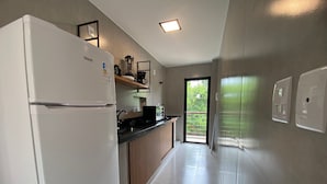 A modern kitchen with a refrigerator, stove, and black countertop. - Villa Visgo Itacaré (Itacaré)