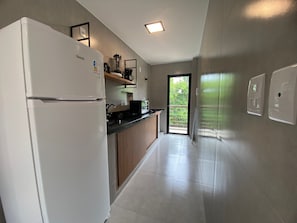 Una cocina moderna con refrigerador, estufa y encimera negra.