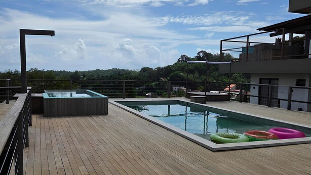 A rooftop pool area with wooden decking, two swimming pools, and a view of a forested hill. - Villa Visgo Itacaré (Itacaré)