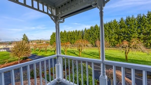 A covered porch with a view of a green landscape and trees. - The Allen House (Ridgefield)