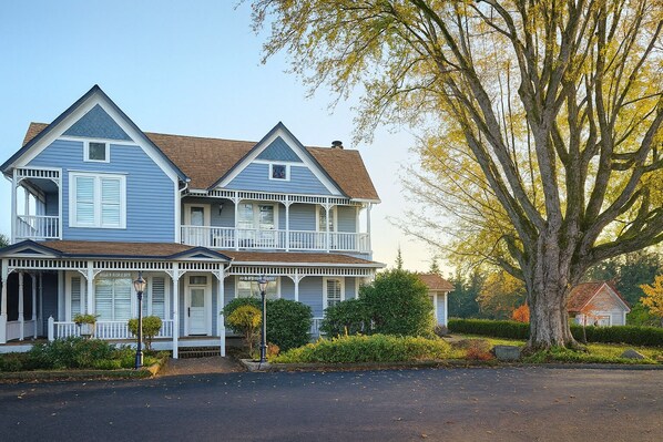 A two-story house with a balcony, a porch, and a large tree in the background. - The Allen House (Ridgefield)