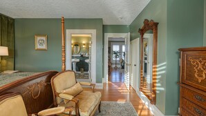 A room with a wooden bed, a sofa, a mirror, and a dresser. - The Allen House (Ridgefield)