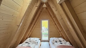A small attic bedroom with two beds, a skylight, and wooden walls.