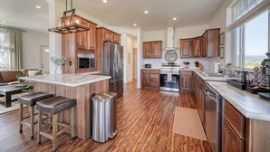 Une cuisine spacieuse dotée de meubles en bois, d’appareils électroménagers en acier inoxydable et d’un grand îlot central avec des tabourets de bar.