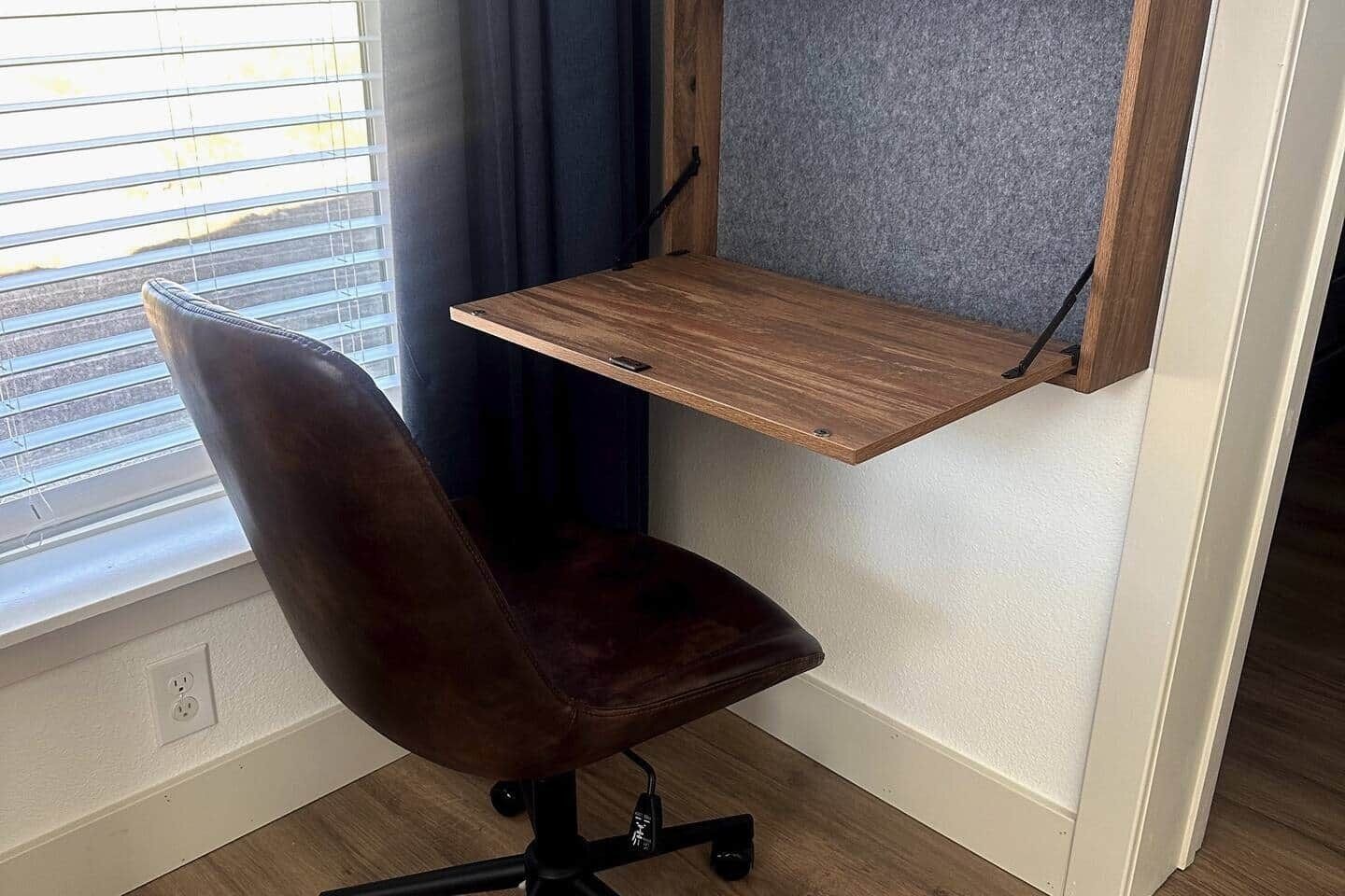 A corner office with a desk, chair, and a window with blinds.