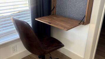 A corner office with a desk, chair, and a window with blinds.
