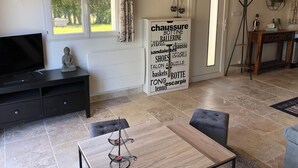 A living room with a television, a Buddha statue, a wooden table, and a sign with various words. - Charming cottage (Monteux)