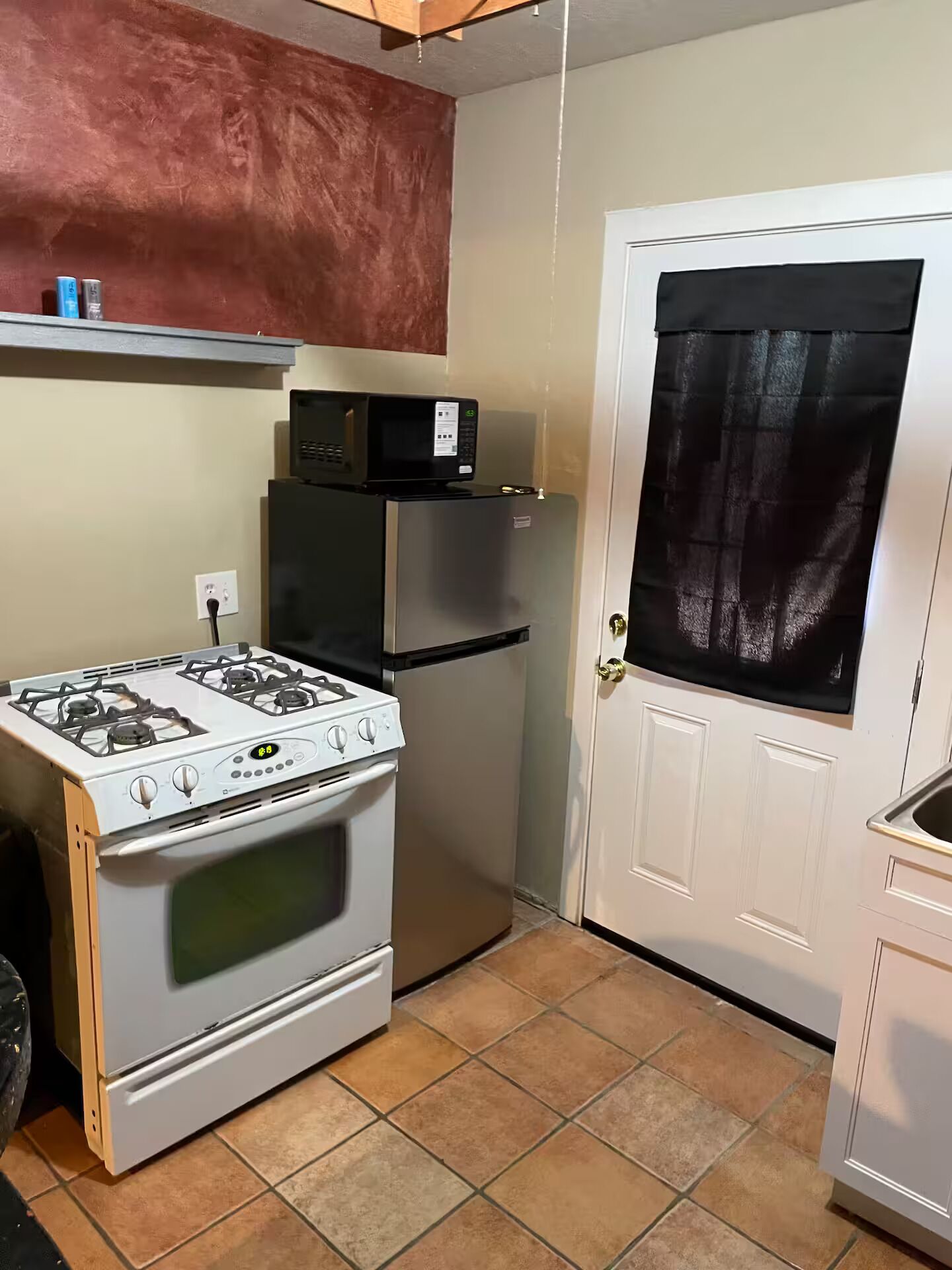 A compact kitchen with a gas stove, a refrigerator, and a microwave.