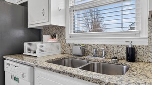 Eine Küche mit Granit Arbeitsplatten, Edelstahlspülen und weißen Schränken.