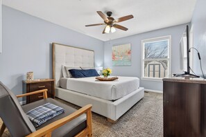 A bedroom with a bed, a desk, a chair, a ceiling fan, and a window with blinds. - Eagles Rest Home • Sleeps 7 • Minutes to Army Base (Oak Grove)