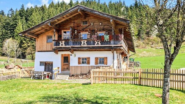 Un chalet en bois à deux étages, doté d’un balcon, d’une entrée principale et d’une clôture en bois dans la cour.