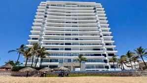 A multi-story hotel with balconies, a beachside location, and palm trees. - 3 bedroom high end beach front condo with amazing view (Mazatlán)
