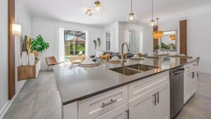 A modern kitchen with a central island, stainless steel appliances, and pendant lighting. - Families Deluxe Dream Vacation, 10 min from Disney (Kissimmee)
