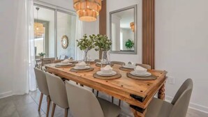 A dining area with a wooden table set for four, surrounded by chairs. - Families Deluxe Dream Vacation, 10 min from Disney (Kissimmee)
