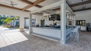An open-plan kitchen with a bar area, ceiling fans, and a patio with a brick floor. - Families Deluxe Dream Vacation, 10 min from Disney (Kissimmee)