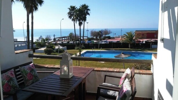 Ein Balkon mit Blick auf einen Swimmingpool und das Meer.