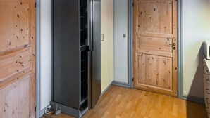 Ein Zimmer mit Holztür, eingebautem Kühlschrank und Holzboden.