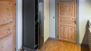 A room with a wooden door, a built-in refrigerator, and a wooden floor.