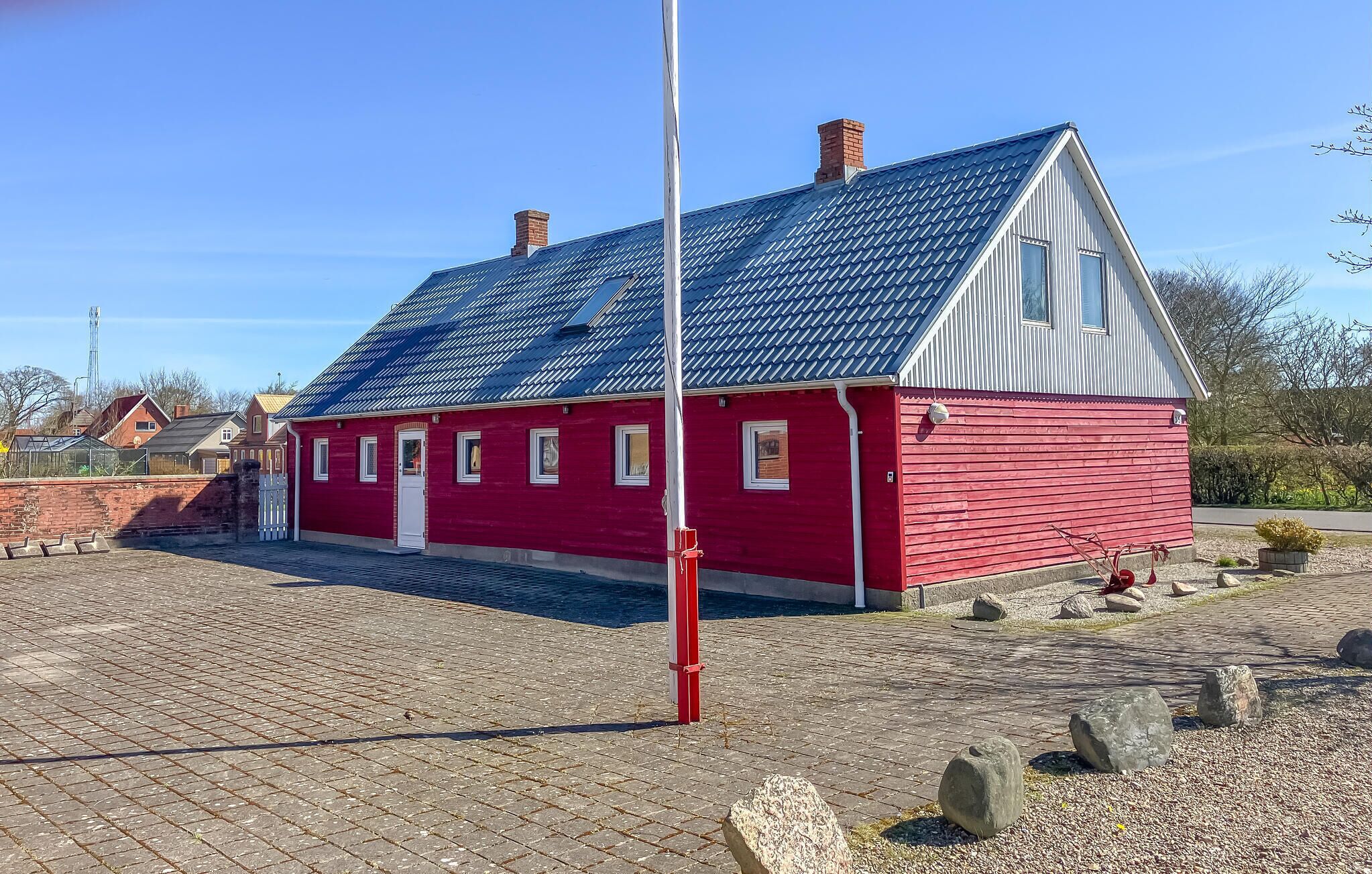 A red building with a sloped roof, a white door, and multiple windows.