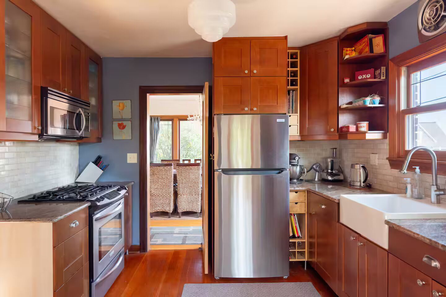 Een moderne keuken met houten kastjes, roestvrijstalen apparatuur en uitzicht op een balkon.